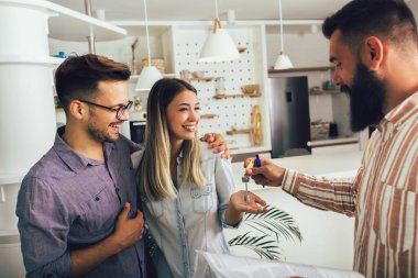 Mutlu genç çift yeni evlerinin anahtarlarını gösteriyor.