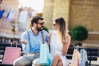 Alışveriş yaptıktan sonra bankta oturan genç çift.