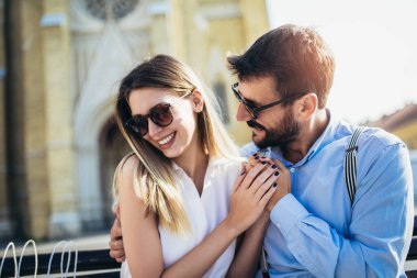 Güzel, genç bir çift bankta oturuyor, sarılıyor ve eğleniyorlar.