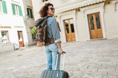  Avrupa 'nın eski şehrinde bavuluyla sokakta yürüyen bir kadın turist..