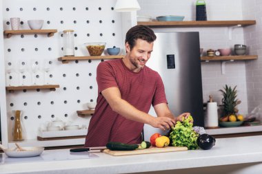 Kafkasyalı genç adam mutfağa sebze kusuyor. Diyet konsepti. Evde yemek pişirmek. Yemek hazırlayın.