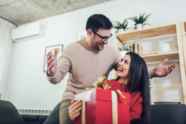 Charming woman accepting present from husband at home