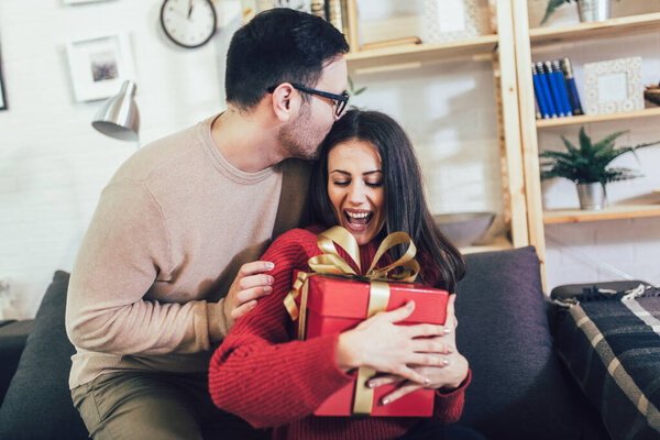 Charming woman accepting present from husband at home
