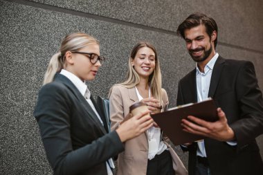 Ofisteki iş arkadaşları ofis binasının yanında konuşuyor, yeni projeyi tartışıyorlar, pano ve dijital tableti tutuyorlar..