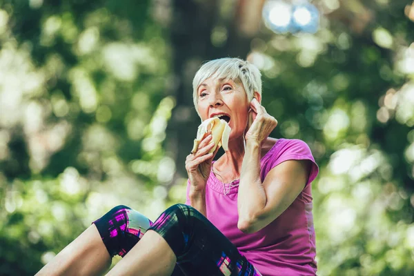 Mulher Sênior Exercitando Parque Enquanto Ouve Música Mulher Madura Comer — Fotografia de Stock