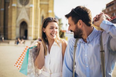 Alışveriş torbalı güzel bir çift şehirde alışveriş yaparken konuşuyor ve gülümsüyor.