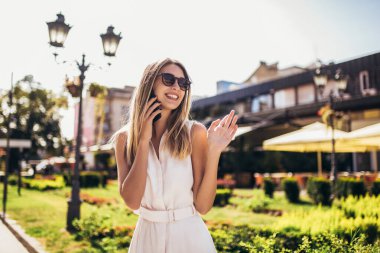 Sokakta telefonla konuşan neşeli bir kadın.