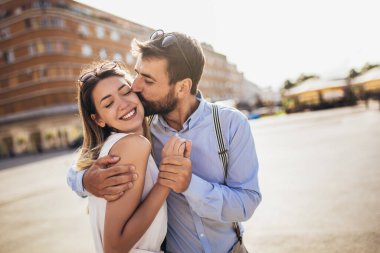 Birbirine aşık çiftler romantik bir yolculukta sokakta kucaklaşıyorlar.
