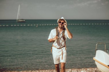 Sırt çantalı, deniz kenarında gülümseyen turist..