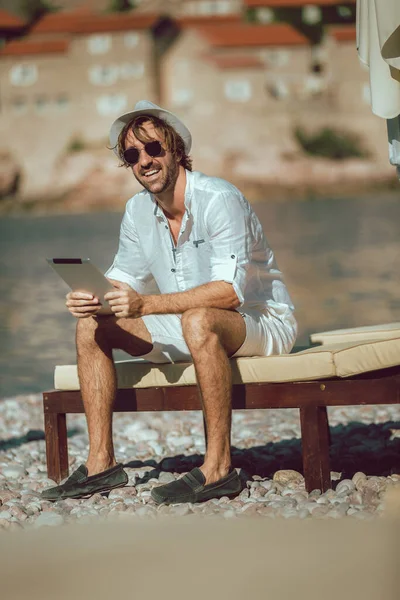 男リラックスして海のビーチでデジタルタブレットを使用 — ストック写真