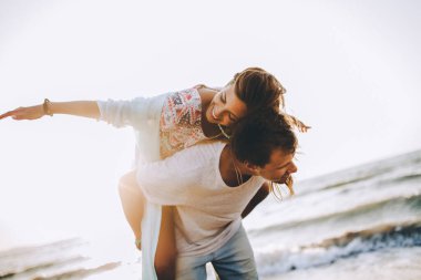 Mutlu gülümseyen yaz çifti kollarını açarak güzel kumsalda sırt sırta geziyor.