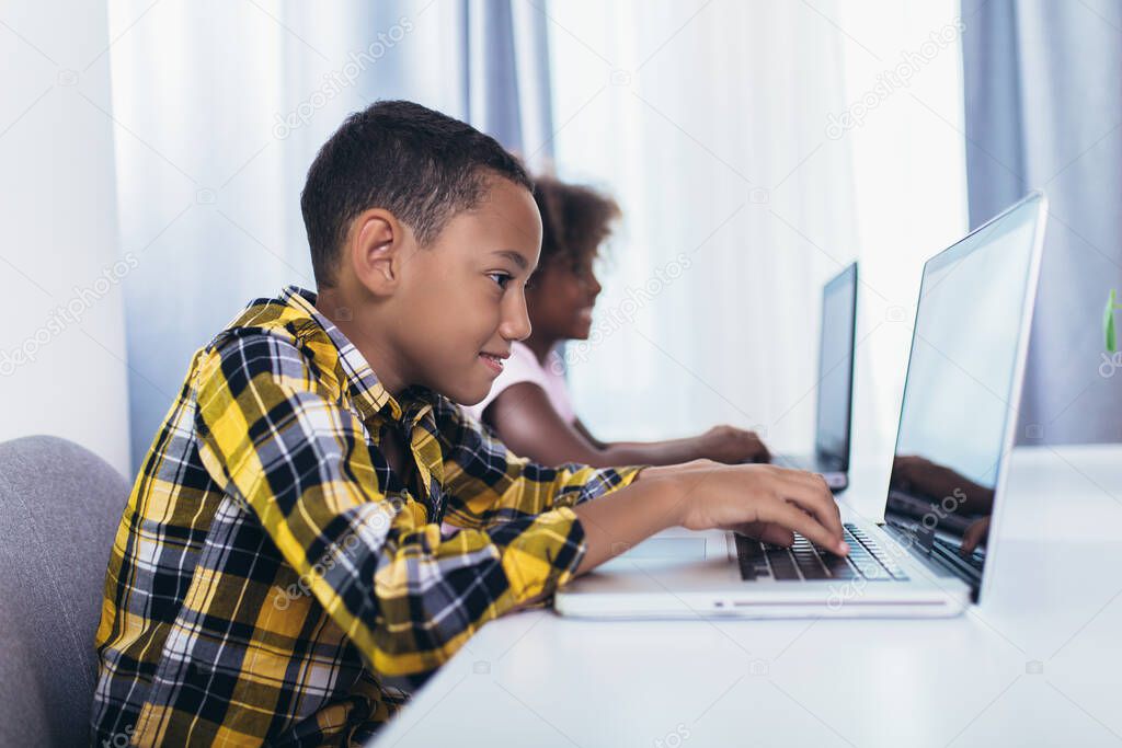 African American elementary students using computer and following classes online due to coronavirus pandemic.
