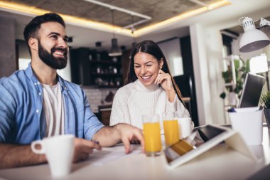 Diz üstü bilgisayar kullanan ve mali durumlarını inceleyen neşeli genç çift. 