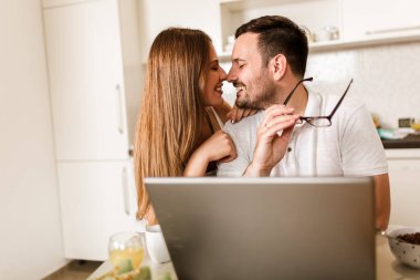 Genç çift evde dizüstü bilgisayar kullanarak vakit geçiriyorlar..