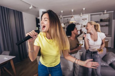 Genç kadın mikrofona şarkı söyleyerek eğleniyor. Bekarlığa veda partisi, karaoke, müzik konseri ve tatil konsepti 