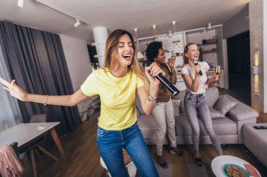 Genç kadın mikrofona şarkı söyleyerek eğleniyor. Bekarlığa veda partisi, karaoke, müzik konseri ve tatil konsepti 