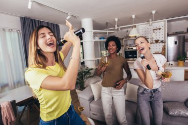 Genç kadın mikrofona şarkı söyleyerek eğleniyor. Bekarlığa veda partisi, karaoke, müzik konseri ve tatil konsepti 