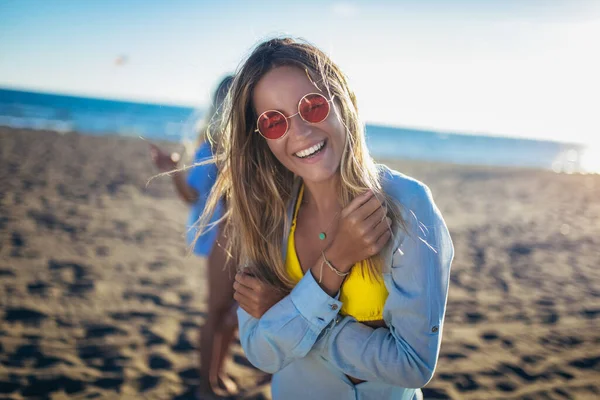 背景に友人と一緒にビーチで幸せな若い女性 ビーチパーティーで楽しんでいる友人のグループ — ストック写真