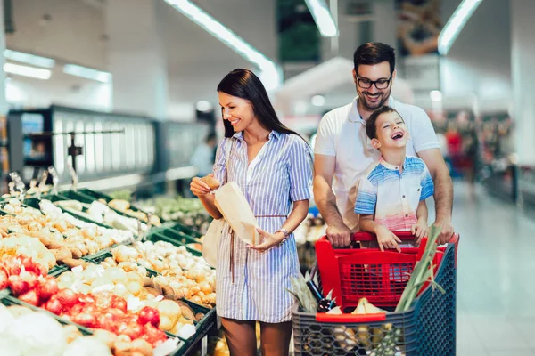 Happy family buying fruit at grocery store or supermarket - shopping, food, sale, consumerism