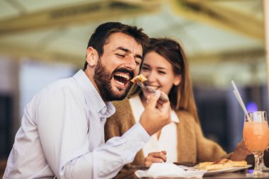 Birlikte restoranda pizzanın tadını çıkaran gülümseyen çift.