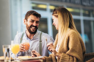 Smiling Couple On Date Enjoying Pizza In Restaurant Together clipart