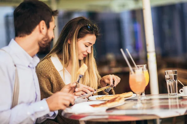 Birlikte restoranda pizzanın tadını çıkaran gülümseyen çift.