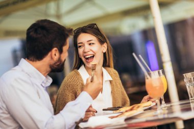Birlikte restoranda pizzanın tadını çıkaran gülümseyen çift.