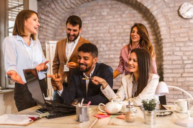 Business team working on new project and smiling. Man and women sitting together in modern office