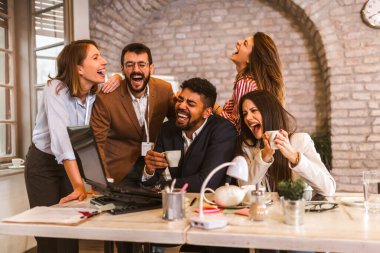 Business team working on new project and smiling. Man and women sitting together in modern office