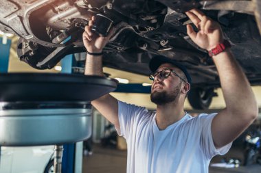 Garajında araba tamir eden bir tamircinin portresi, yağ değişimi..