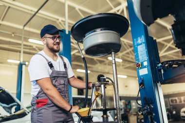 Garajında araba tamir eden bir tamircinin portresi, yağ değişimi..