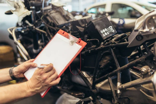 Een Man Schrijft Een Klembord Een Garage Professionele Motorfiets Monteur — Stockfoto