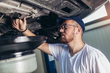 Garajında araba tamir eden bir tamircinin portresi, yağ değişimi..