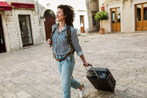 Young woman with suitcase in old city on vacation