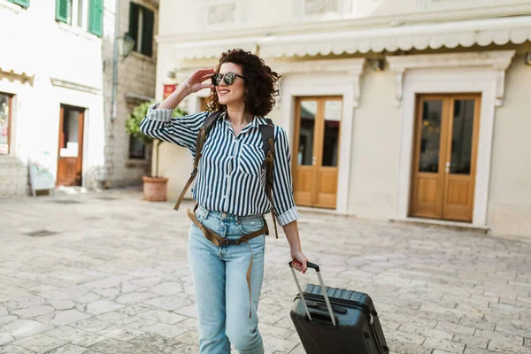 Young woman with suitcase in old city on vacation