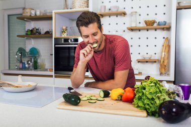 Kafkasyalı genç adam mutfağa sebze kusuyor. Diyet konsepti. Evde yemek pişirmek. Yemek hazırlayın.