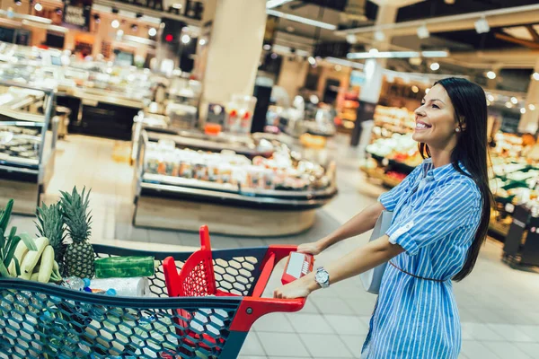 Молода Жінка Купує Супермаркеті Штовхаючи Візок Усміхаючись — стокове фото