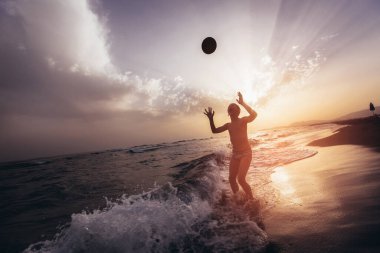 Gün batımında top oynayan çocuk silueti. Seçici odak