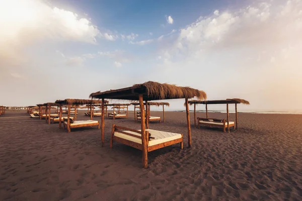 Sandy beach with sun beds at sunset