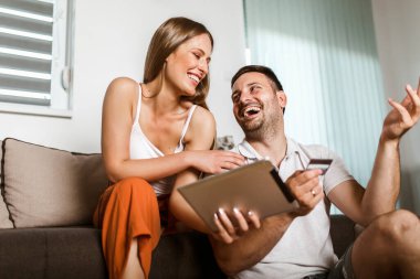 Mutlu genç çift tabletle online alışveriş yapıyor.