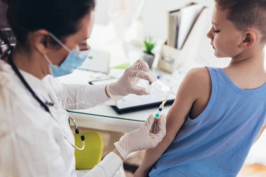 Coronavirus aşısı. Covid-19 aşısı. Çocuk aşılayan doktor. Küçük çocuk grip aşısı oluyor..