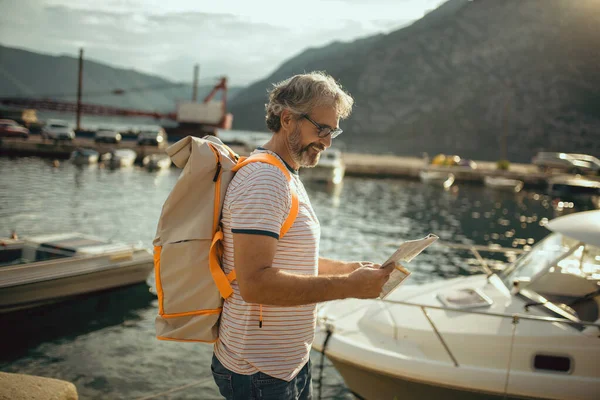 Uśmiechnięty Turysta Dojrzały Mężczyzna Stojący Mapą Plecakiem Nad Morzem — Zdjęcie stockowe