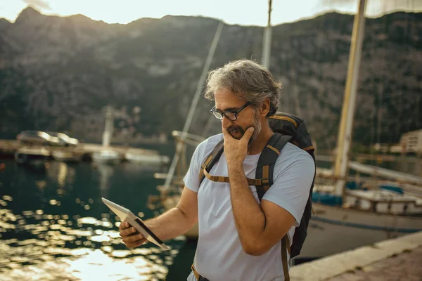 Mosolygós Turista Érett Férfi Áll Digitális Tabletta Hátizsák Tenger Közelében — Stock Fotó