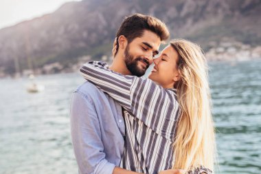 Mutlu genç çift sahilde gülüyor ve sarılıyor.