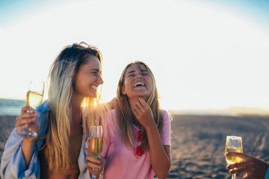 Mutlu genç kadınlar sahildeki bekarlığa veda partisinde şampanya içiyorlar.