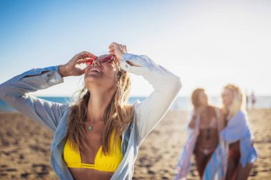 Üç güzel kız sahilde eğleniyor.