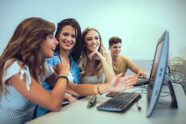 Üniversite öğrencileri sınıfta oturup, ders sırasında bilgisayar kullanıyorlar..