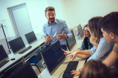 Üniversite öğrencileri sınıfta oturup, ders sırasında bilgisayar kullanıyorlar..