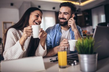 Evde çalışan genç çift dizüstü bilgisayar ve dijital tablet kullanıyor.