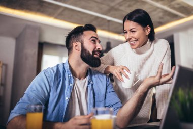 Evde çalışan genç çift dizüstü bilgisayar ve dijital tablet kullanıyor.